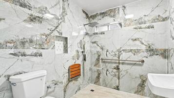 Une salle de bain comprenant des toilettes, un lavabo et un espace douche.