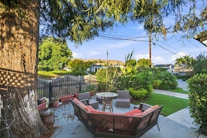 A patio with outdoor furniture, a tree, and a view of a residential area.