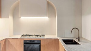 A modern kitchen with a built-in gas stove, oven, and stainless steel sink. - Casa Vista, Dandenong Ranges forest retreat (Kalorama)
