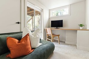 A room with a green sofa, a white chair, a desk with a computer monitor, and a small plant. - Casa Vista | Dandenong Ranges 5BR, Sleeps 10 (Kalorama)