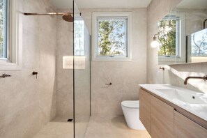 A modern bathroom with a glass shower enclosure, a toilet, and a sink with a wooden vanity.