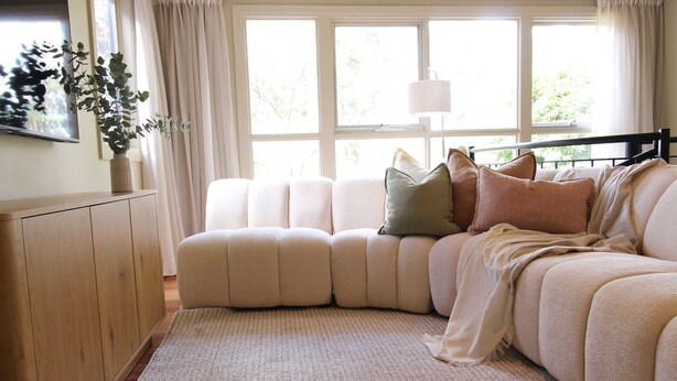 A cozy living room with a sectional sofa, a wooden cabinet, and a large window with curtains. - Casa Vista, Dandenong Ranges forest retreat (Kalorama)