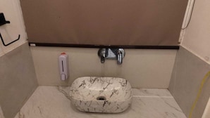 Un baño con lavamanos de mármol, dispensador de jabón y grifo.