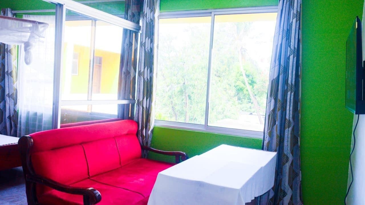 Una habitación con un sofá rojo, una mesita y una ventana con cortinas.