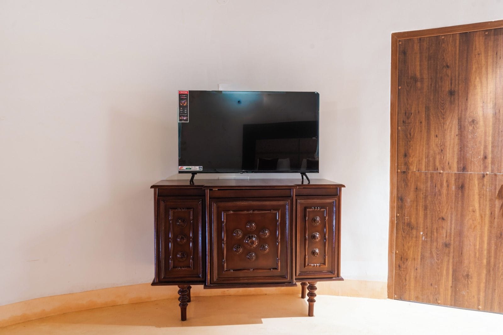 Un mueble de madera con un televisor de pantalla plana encima, colocado frente a una pared lisa.