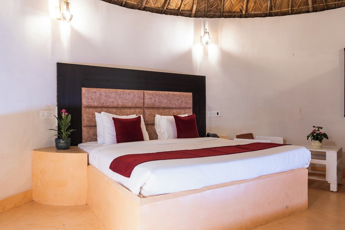 Una habitación de hotel con una cama grande, una mesita de noche y una lámpara de pared.