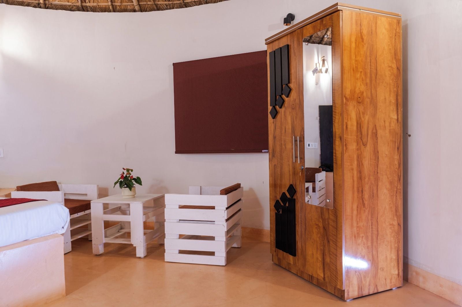 Una habitación con una cama, una mesita de noche con una planta, un armario y un espejo.