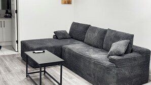 A modern living room with a grey sectional sofa, a small table, and two wall-mounted paintings.