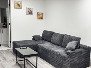 Een moderne woonkamer met een grijze modulaire bank, een klein tafeltje en twee aan de muur bevestigde schilderijen.