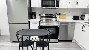 A modern kitchen with stainless steel appliances, a marble backsplash, and a dining area with a table and chairs.