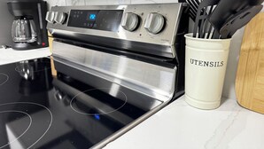 A stainless steel range with a digital display, a coffee maker, and a utensil holder on a kitchen counter.
