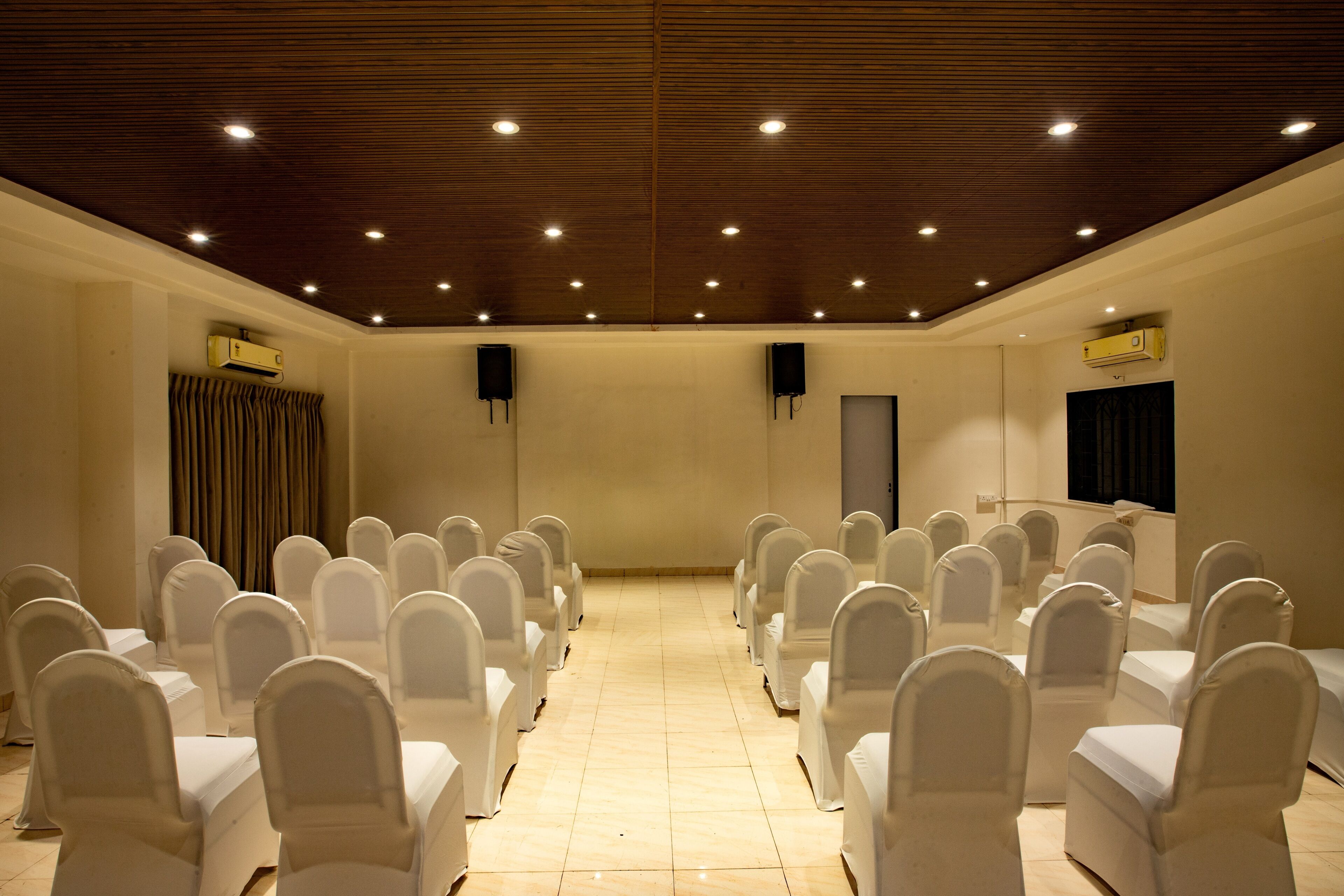 Un salón de conferencias con filas de sillas, un atril y luces en el techo.
