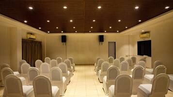 Un salón de conferencias con filas de sillas, un atril y luces en el techo.
