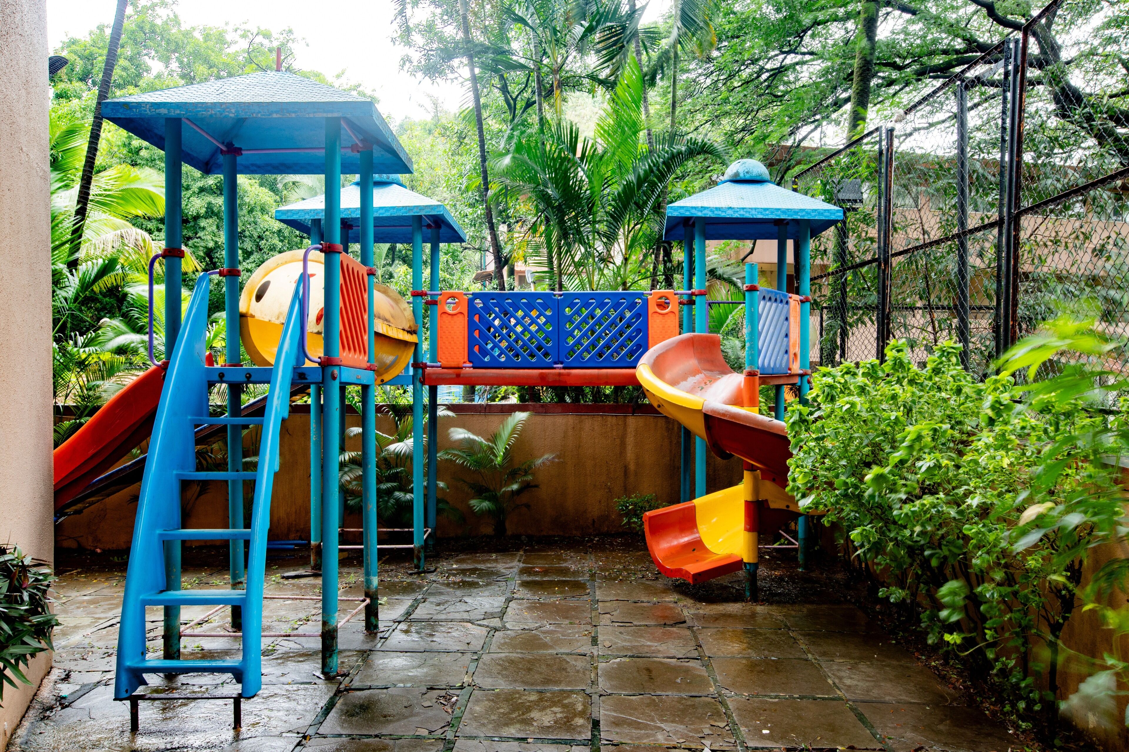 Un parque infantil con toboganes y estructuras para escalar, rodeado de follaje.