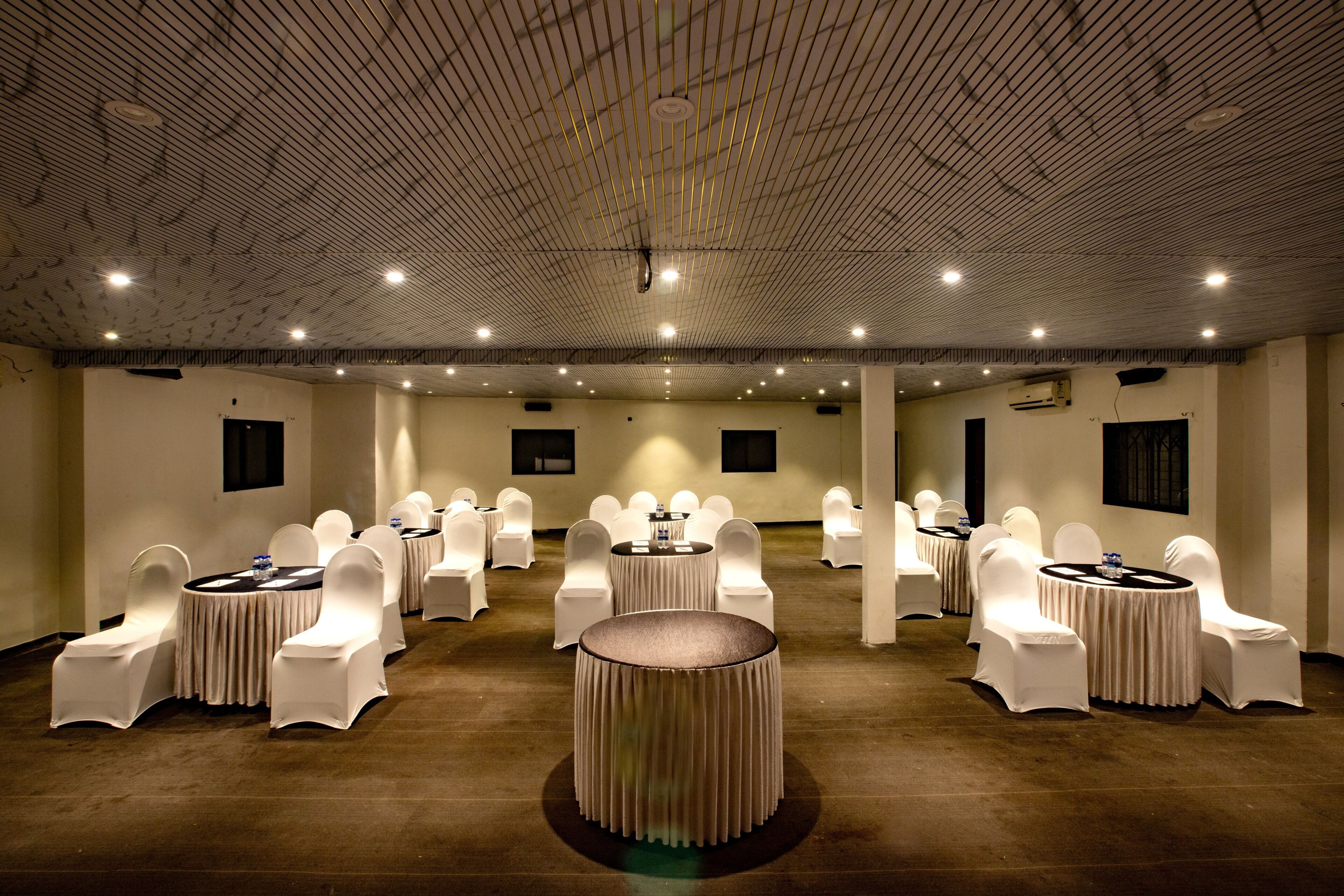 A conference room with round tables, white chairs, and a central decorative column.