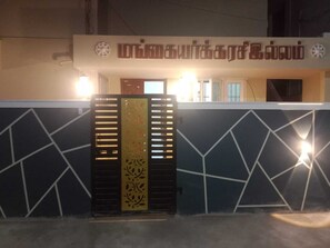 A building entrance with a decorative gate and a sign above. - Mangai Homestay — A Quiet, Nature-Led Stay in Tiruchendur (Thiruchendur)