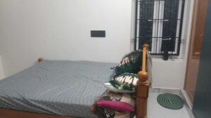 Uma cama de solteiro com estrutura de madeira, colchão cinza estampado e cabeceira de madeira.
