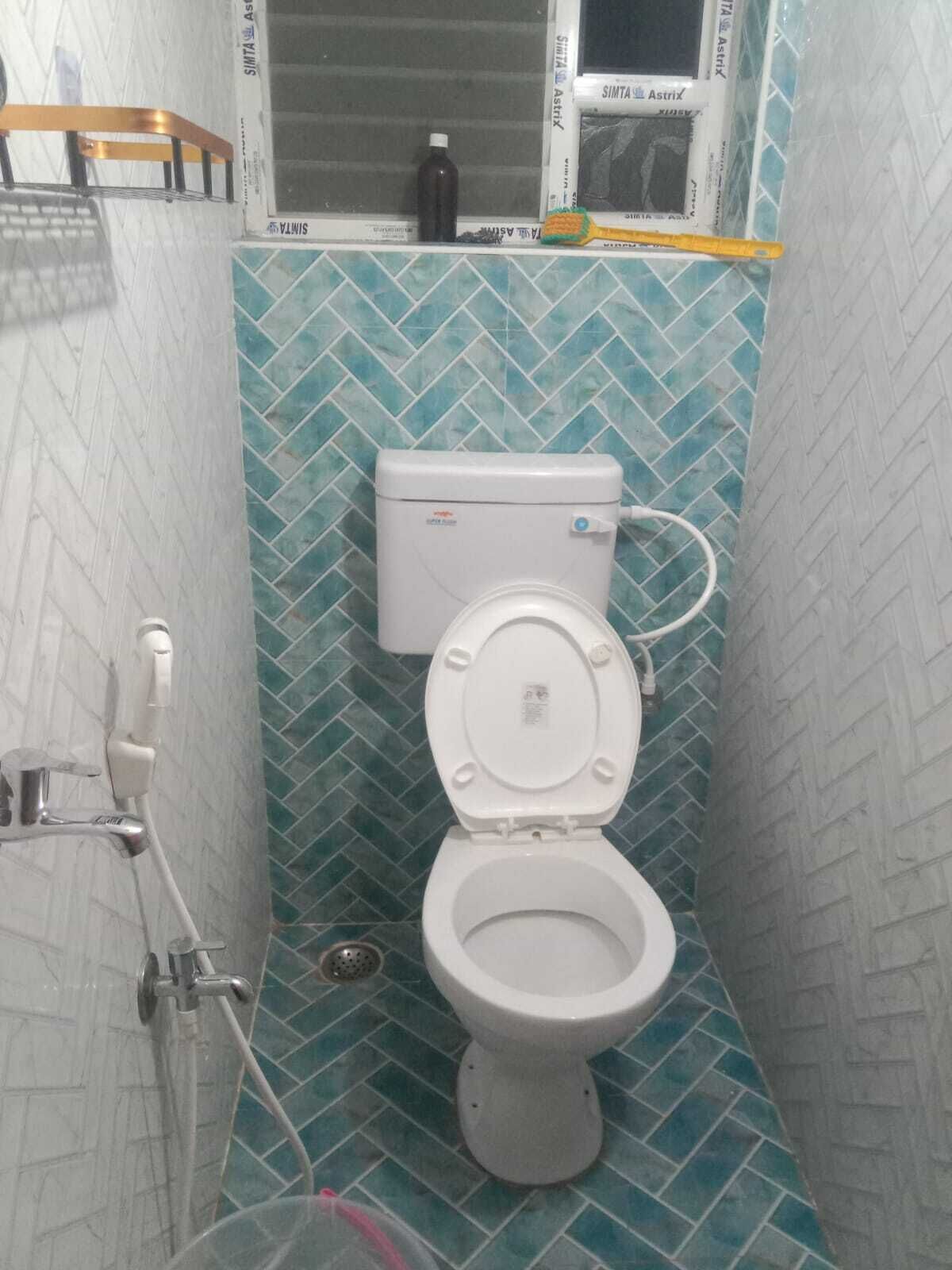 Une petite salle de bain avec des toilettes, une douche et une fenêtre.