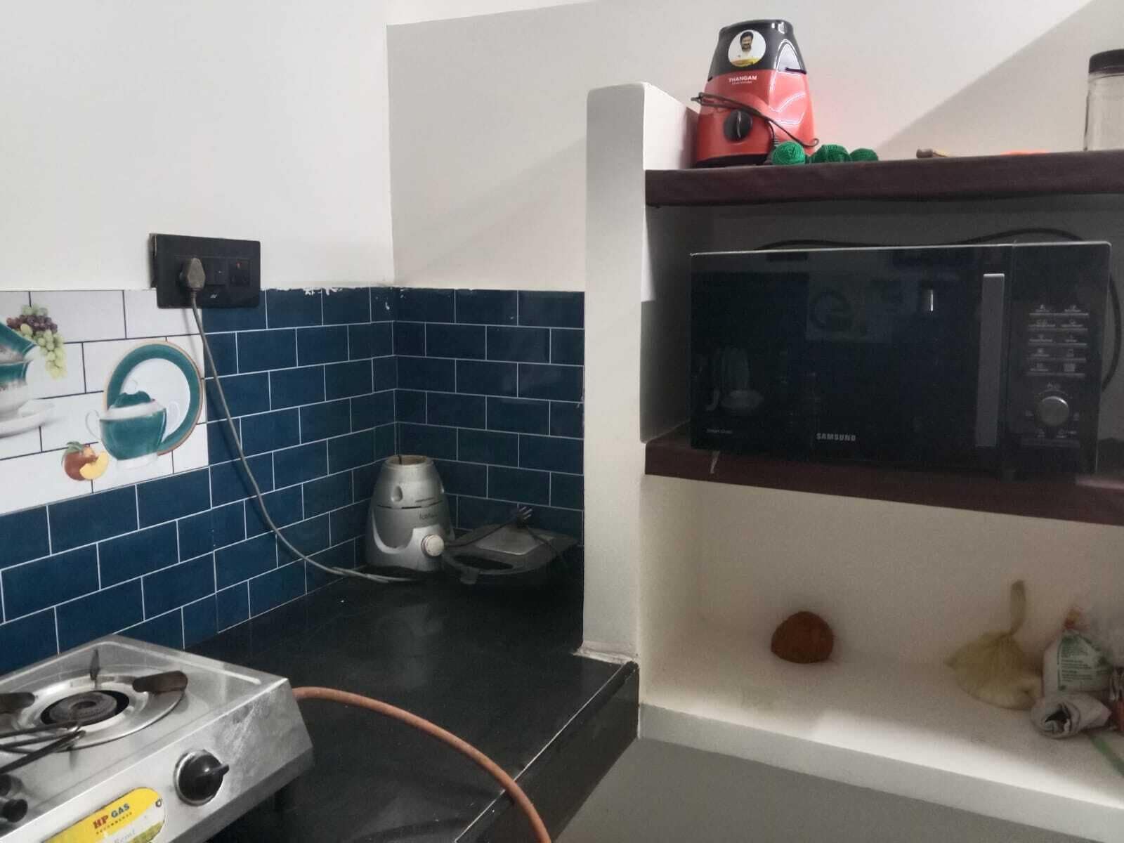 Eine Küche mit einem Gasherd, einer Mikrowelle und einem Wasserkocher auf der Arbeitsplatte.