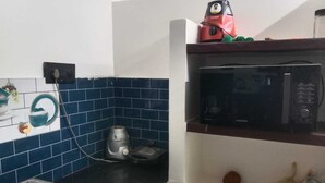 Cozinha com fogão a gás, micro-ondas e chaleira sobre a bancada.
