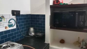 Eine Küche mit einem Gasherd, einer Mikrowelle und einem Wasserkocher auf der Arbeitsplatte.