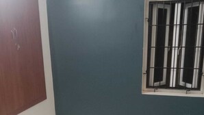 A room with a marble floor, a wooden door, and a window with metal bars.