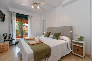 Ein Hotelzimmer mit Bett, Stuhl, Nachttisch mit Lampe, einer kleinen Pflanze und Blick ins Freie.