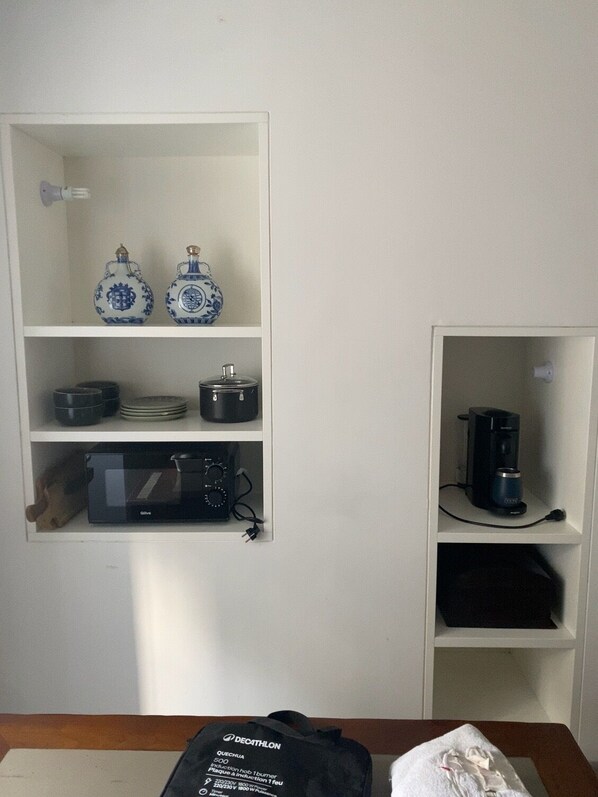 A kitchen with white cabinets, two blue and white ceramic jars, a black coffee maker, and a microwave.