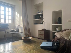 A room with a desk, chair, laptop, and a bed with pillows.