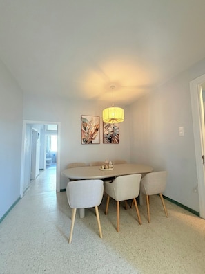 A dining area with a round table, four chairs, and a hanging light fixture. - Blu Windows Rhodes (Rodos)