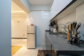 Una cocina moderna con horno empotrado, cafetera y un soporte para cuchillos.