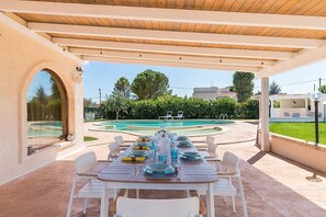 An outdoor dining area with a pool and a covered pergola. - Villa Velar: A bright trullo in the characteristic style of the Apulian countryside, with Free WI-FI. (Carovigno)