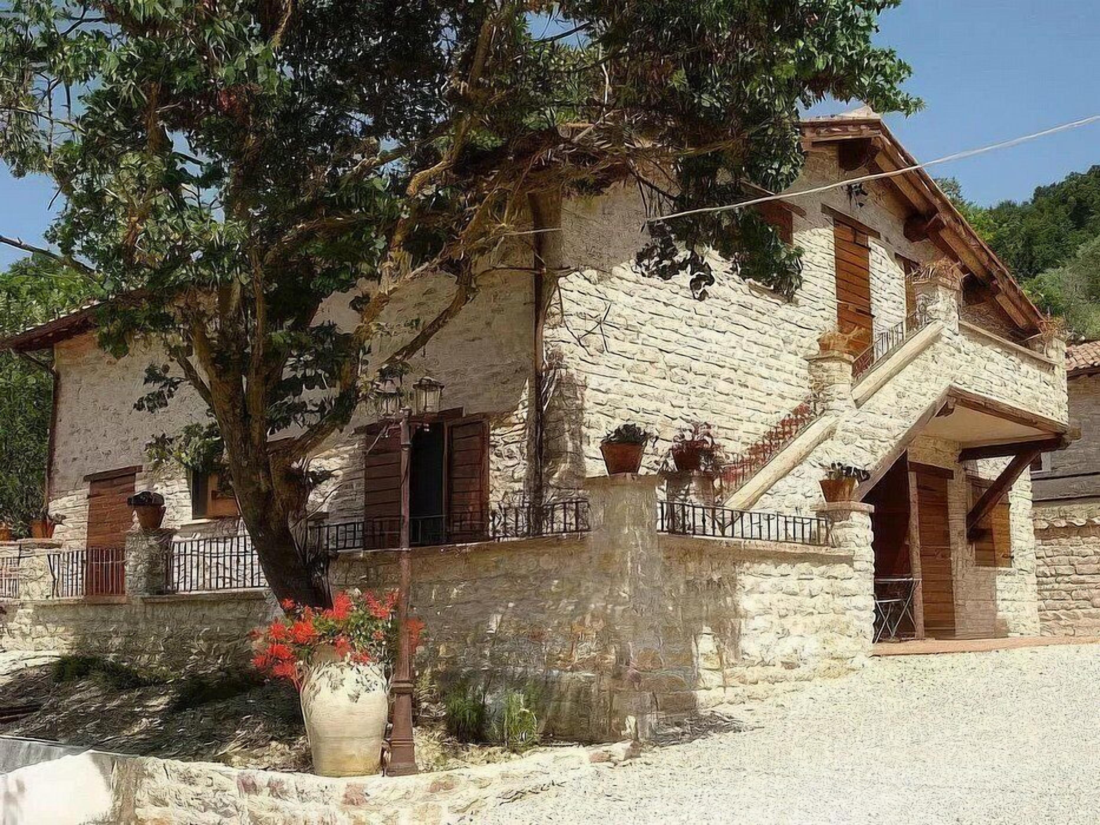 A stone building with a staircase, a tree, and a flower pot.