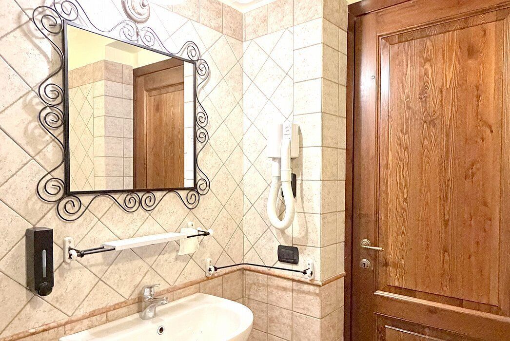 A bathroom with a sink, mirror, towel rack, and a wooden door.