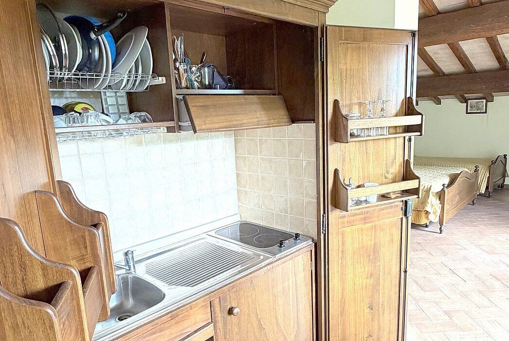 Cucina con mobili in legno, un lavello e uno scolapiatti.