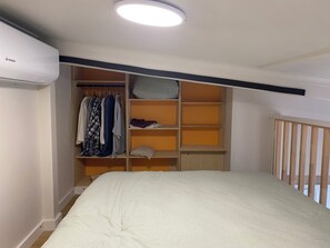 Een slaapkamer met een bed, een kledingkast en een inbouwkast met planken.