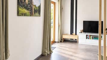 Ein großzügiger Wohnbereich mit einem großen Flachbildfernseher, einer hölzernen Bank und einem Gemälde an der Wand.