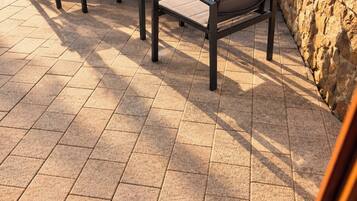 An outdoor patio with a stone wall, a table, and four chairs.