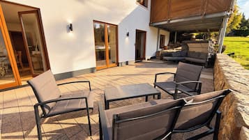 An outdoor patio with a seating area, including chairs and a table, and a covered section with a grill.