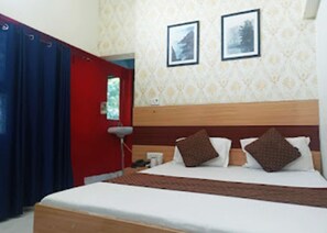 Una habitación de hotel con cama, mesita de noche, lámpara y puerta roja.