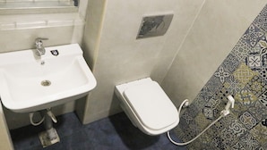 Un baño con lavamanos blanco, inodoro y pared con diseño.