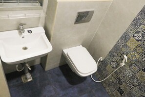 Een badkamer met een wit wastafel, toilet en een muren met een patroon.