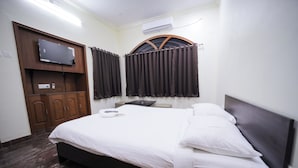 Habitación de hotel con una cama, un televisor montado en un mueble de madera y un equipo de aire acondicionado en la pared.