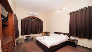Una habitación de hotel con cama, mesita de noche, silla y armario.