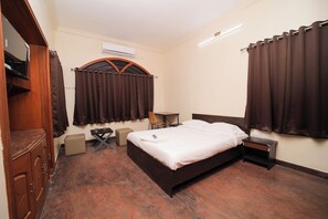 Een hotelkamer met een bed, nachtkastje, stoel en kledingkast.