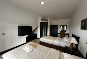 Ein Hotelzimmer mit zwei Betten, einem Flachbildfernseher, einem Schreibtisch mit Lampe und einem Spiegel.