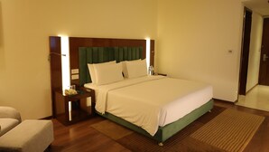 A hotel room with a large bed, bedside tables, a nightstand, and a chair.