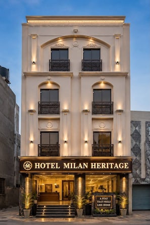 Een hotel met een klassiek gevelontwerp, met een opvallende entree waarop het bord 'HOTEL MILAN HERITAGE' staat.