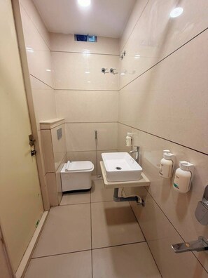 Een compacte, moderne badkamer met toilet, wastafel en bidet.
