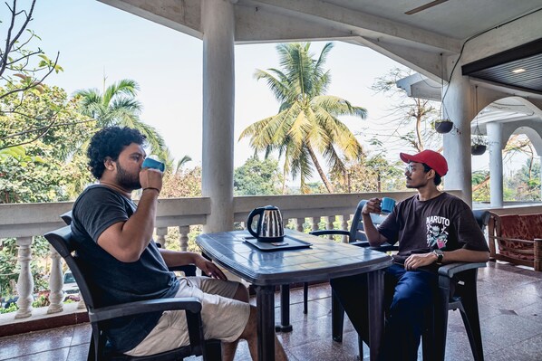 Two individuals seated at a table with a view of palm trees and a building in the background.